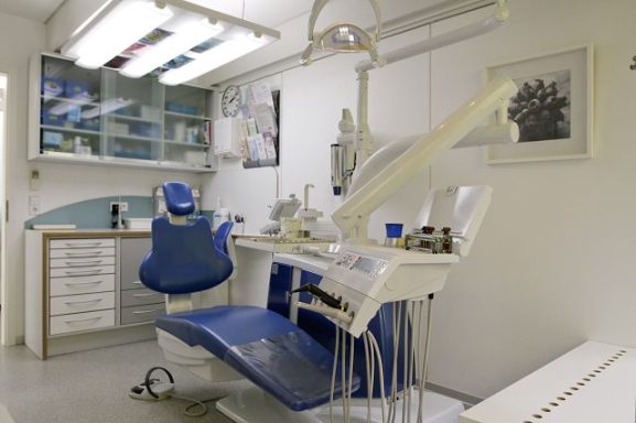 Zahnarztpraxis mit Behandlungsstuhl, Instrumenten und Arbeitsfläche.
